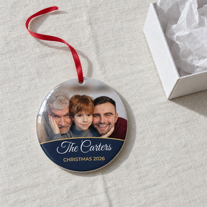 Midnight blue personalised family photo bauble on a tablecloth beside a white gift box