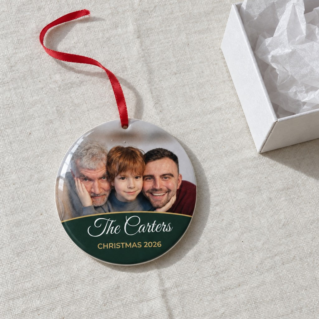 Forest green personalised family photo bauble on a tablecloth beside a white gift box