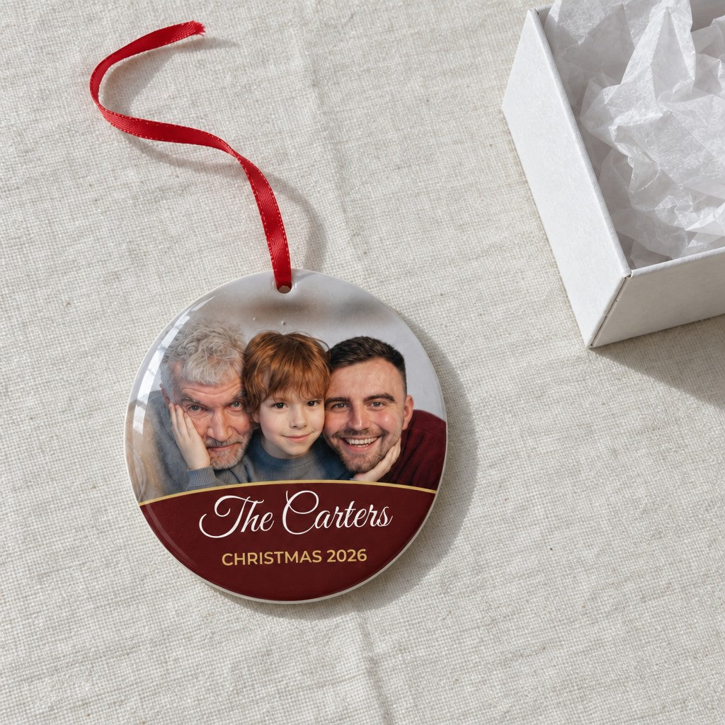 Berry red personalised family photo bauble on a tablecloth beside a white gift box