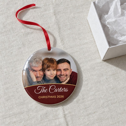 Berry red personalised family photo bauble on a tablecloth beside a white gift box