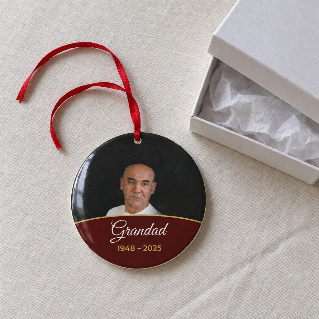 Berry red personalised memorial photo bauble on a tablecloth beside a white gift box