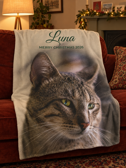 Cream personalised photo blanket with a tabby cat and the name Luna, draped over a red velvet sofa by a fireplace